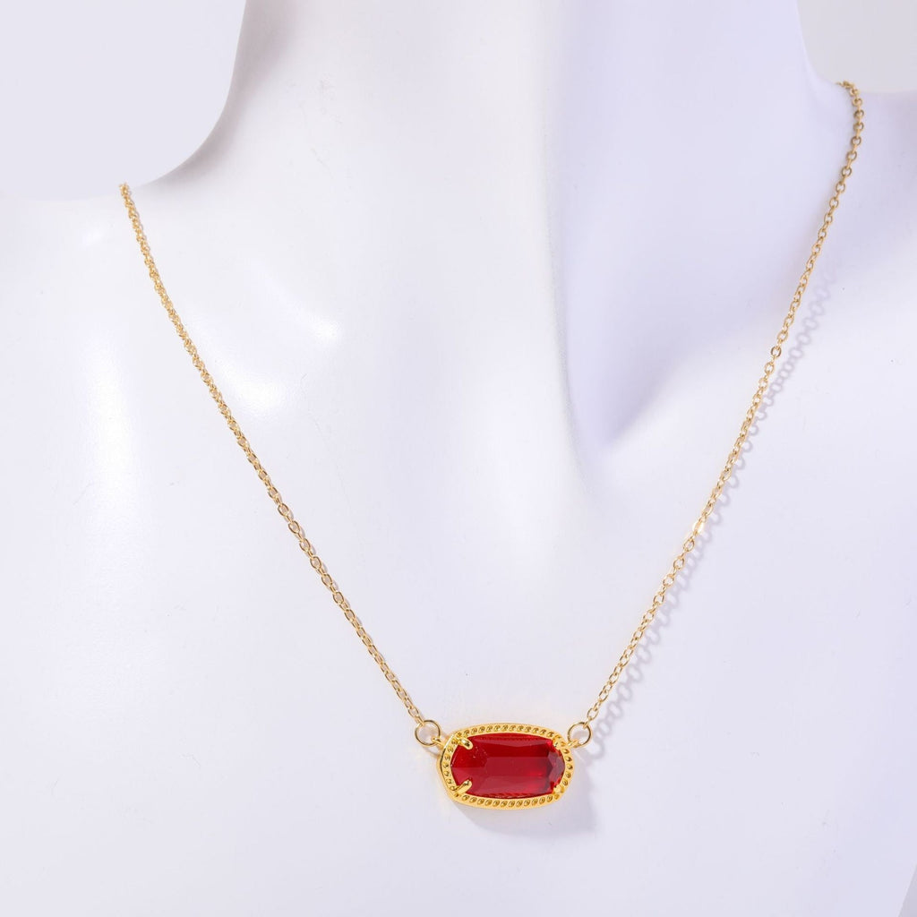 Gold necklace with a red pendant on a white background