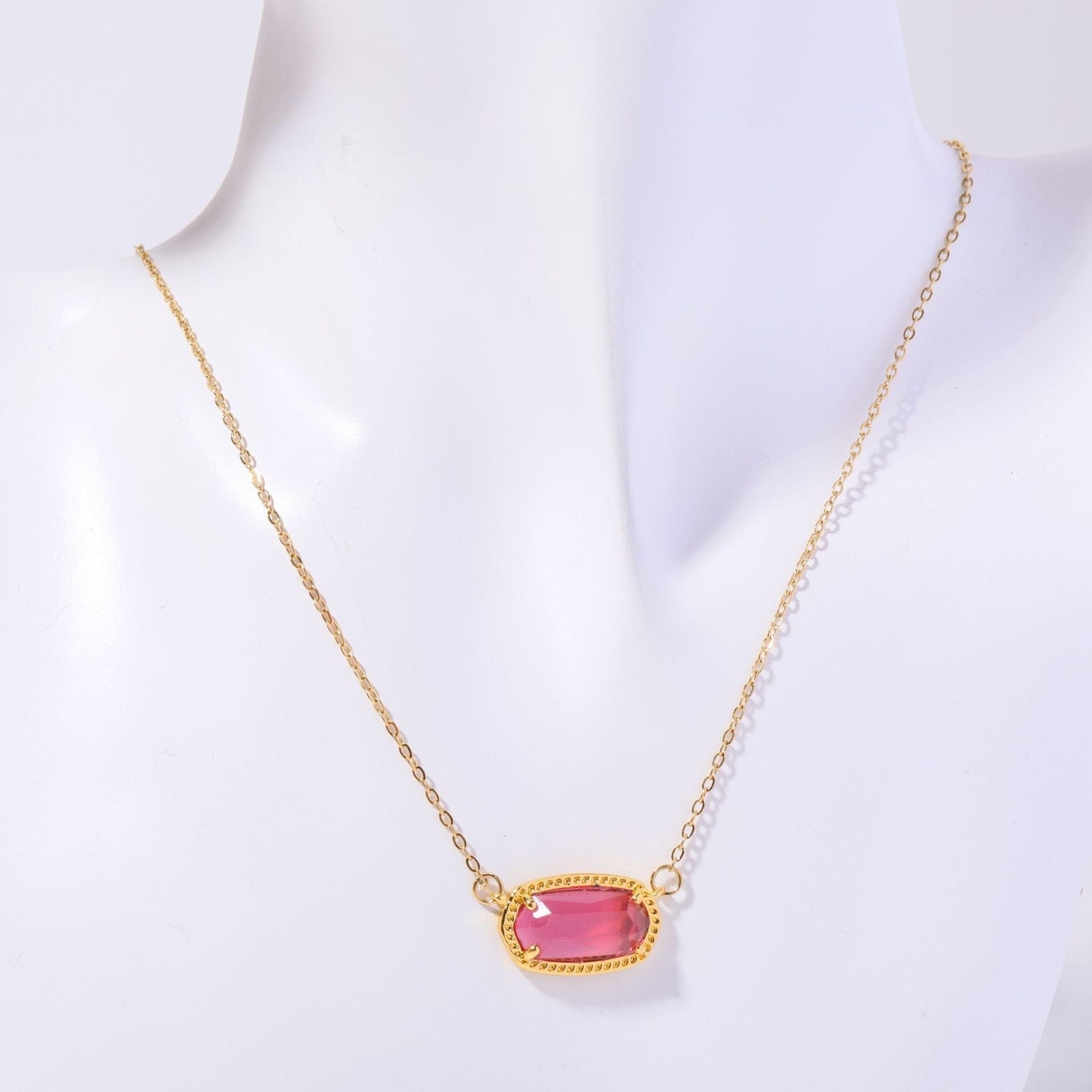 Gold necklace with a pink gemstone on a white background