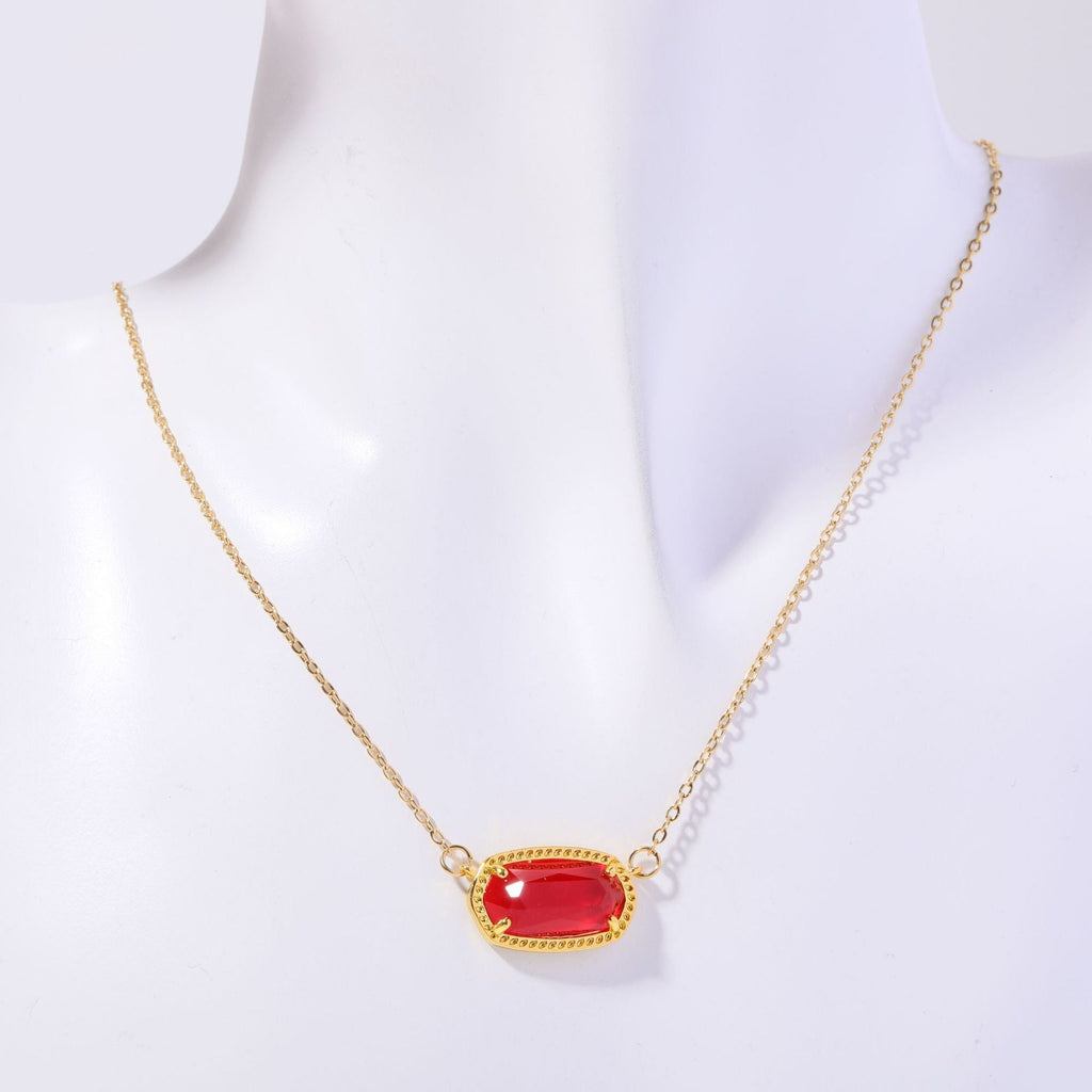 Gold necklace with a red gemstone on a white background