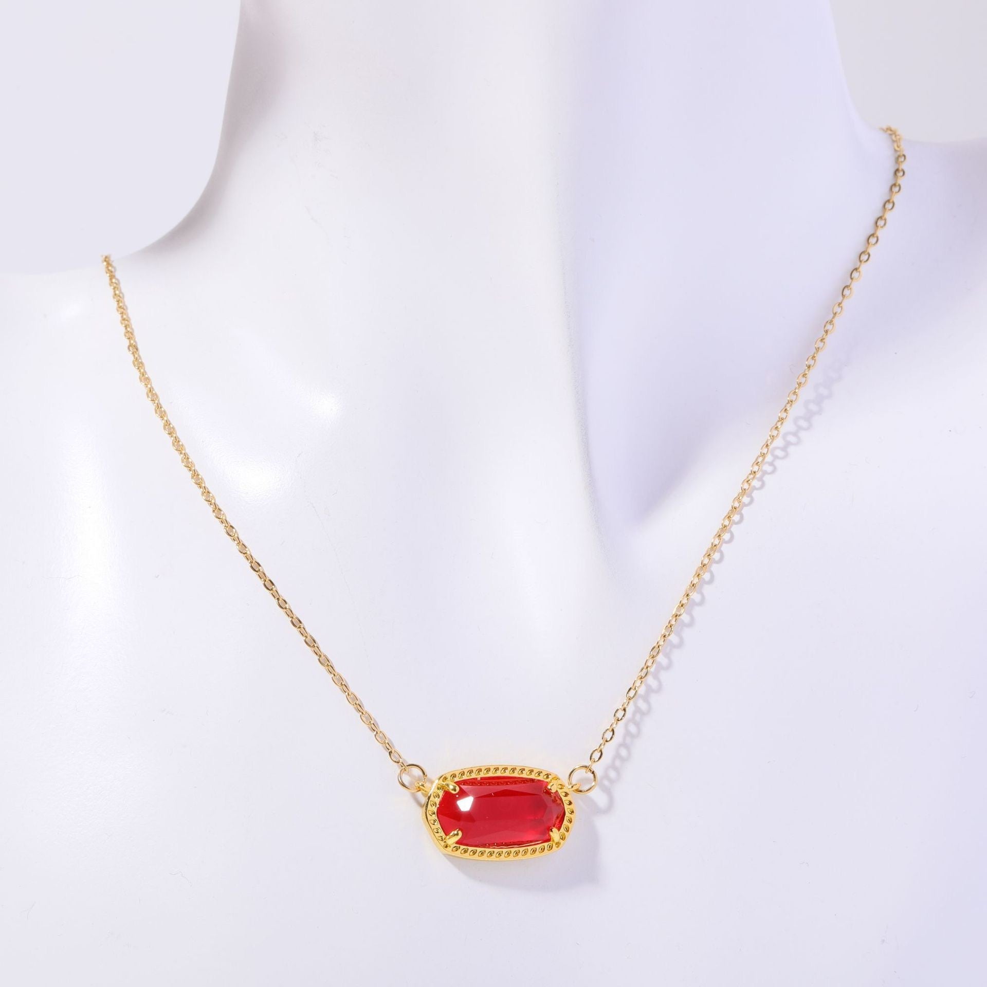 Gold necklace with a red gemstone on a white background