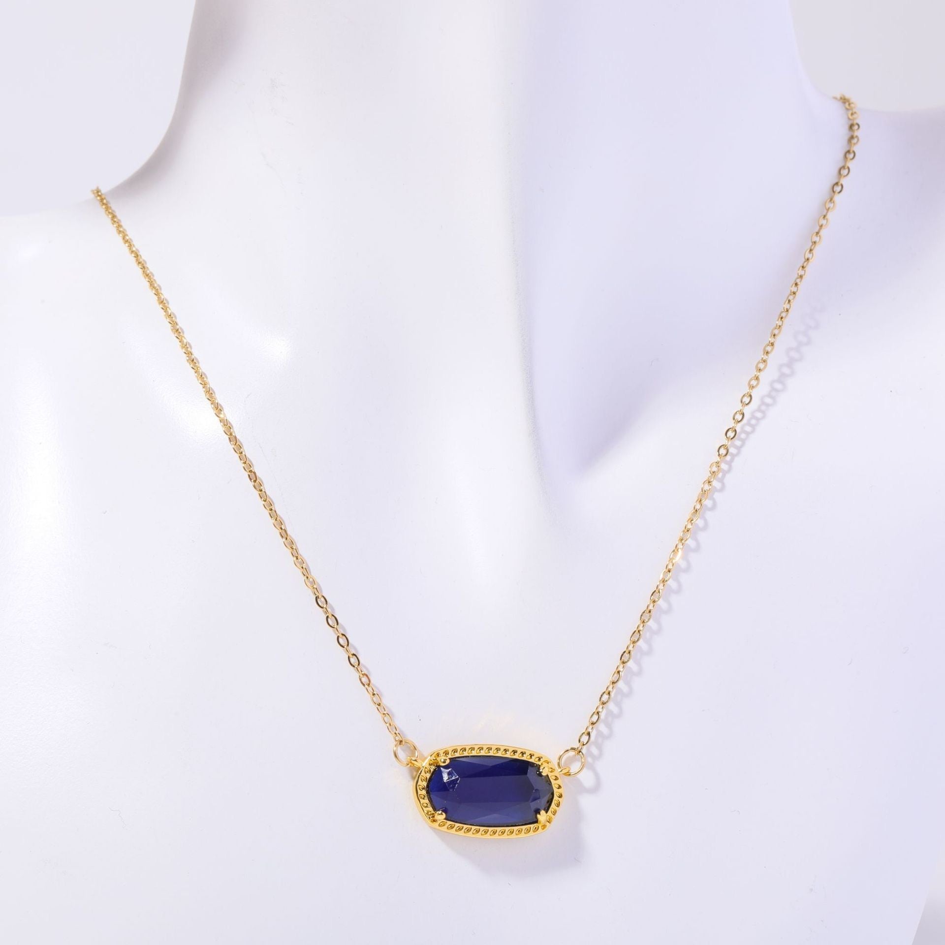 Gold necklace with a blue pendant on a white background