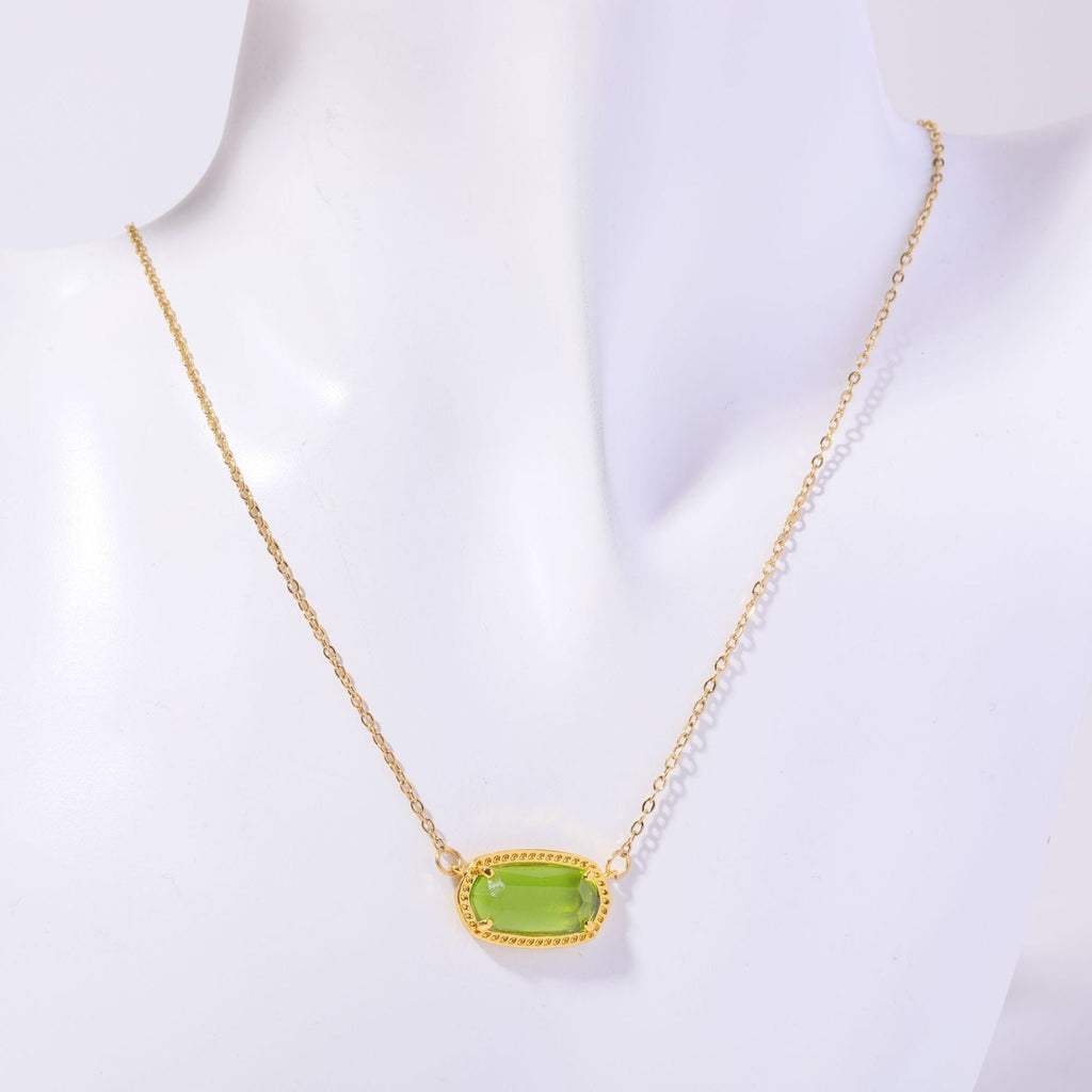 Gold necklace with a green pendant on a white background