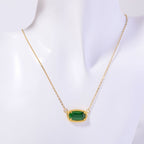 Gold necklace with a green gemstone pendant on a white background