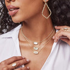 Woman wearing gold necklaces and earrings with a white shirt