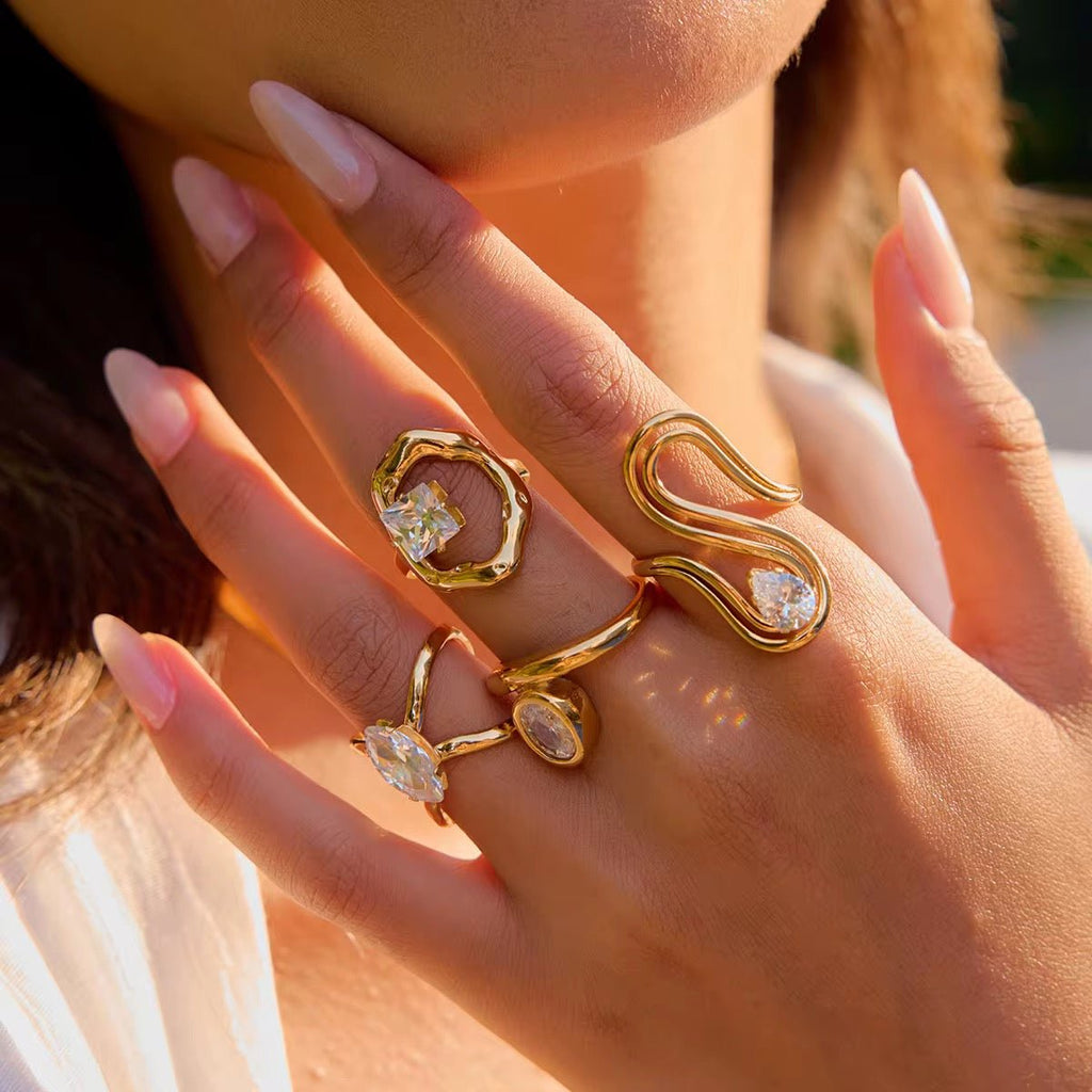 Close-up of a hand wearing gold rings with gemstones, blurred background