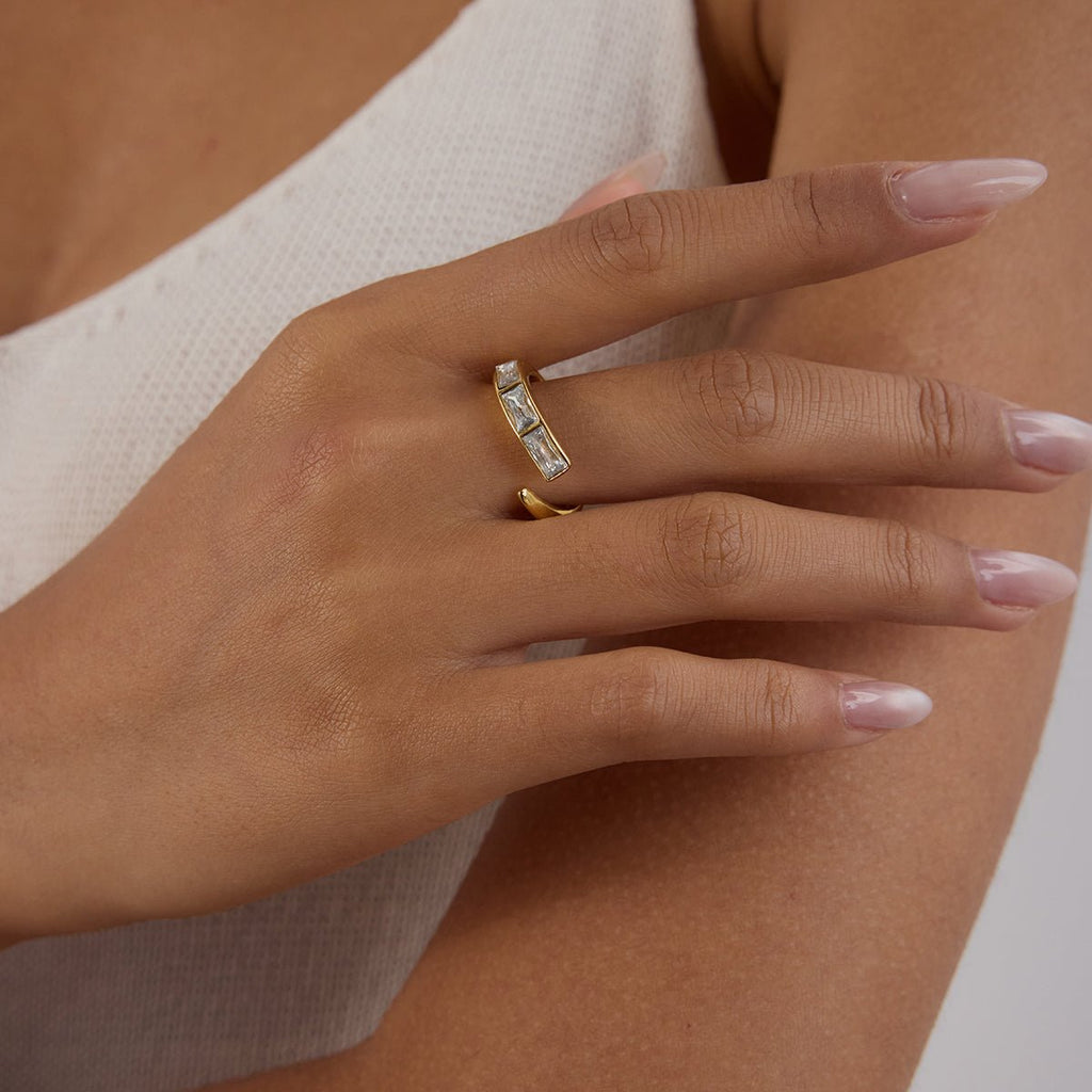 Hand wearing a gold ring with a beige background