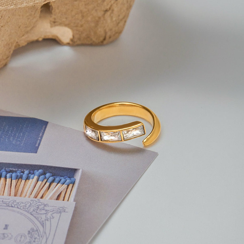 Gold ring with embedded stones on a light surface with matches and paper.