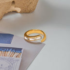 Gold ring with embedded stones on a light surface with matches and paper.