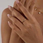 Close-up of a hand wearing a gold ring with a blurred background