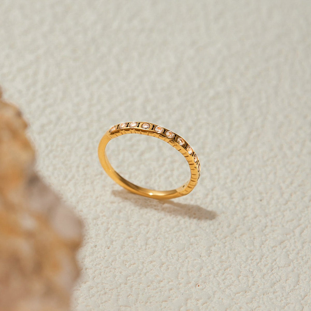 Gold ring with small stones on a textured beige surface