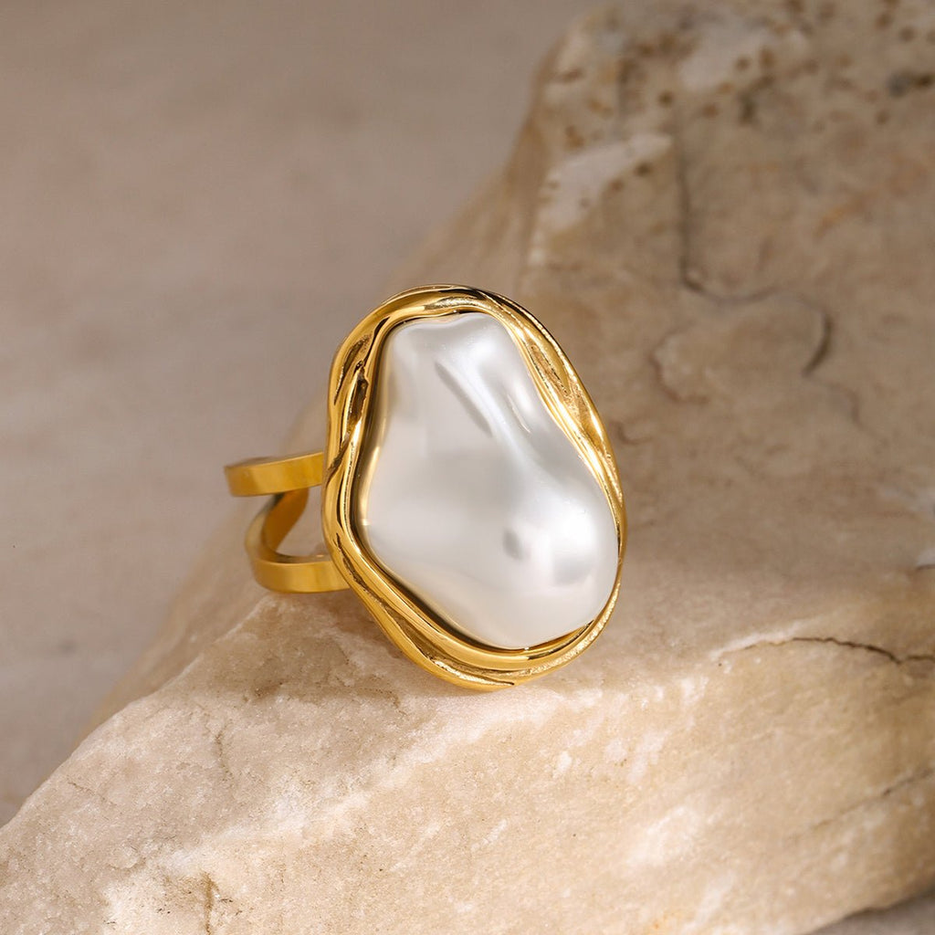 Gold ring with a large pearl on a stone surface