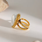 Two gold rings with a white stone on a light background
