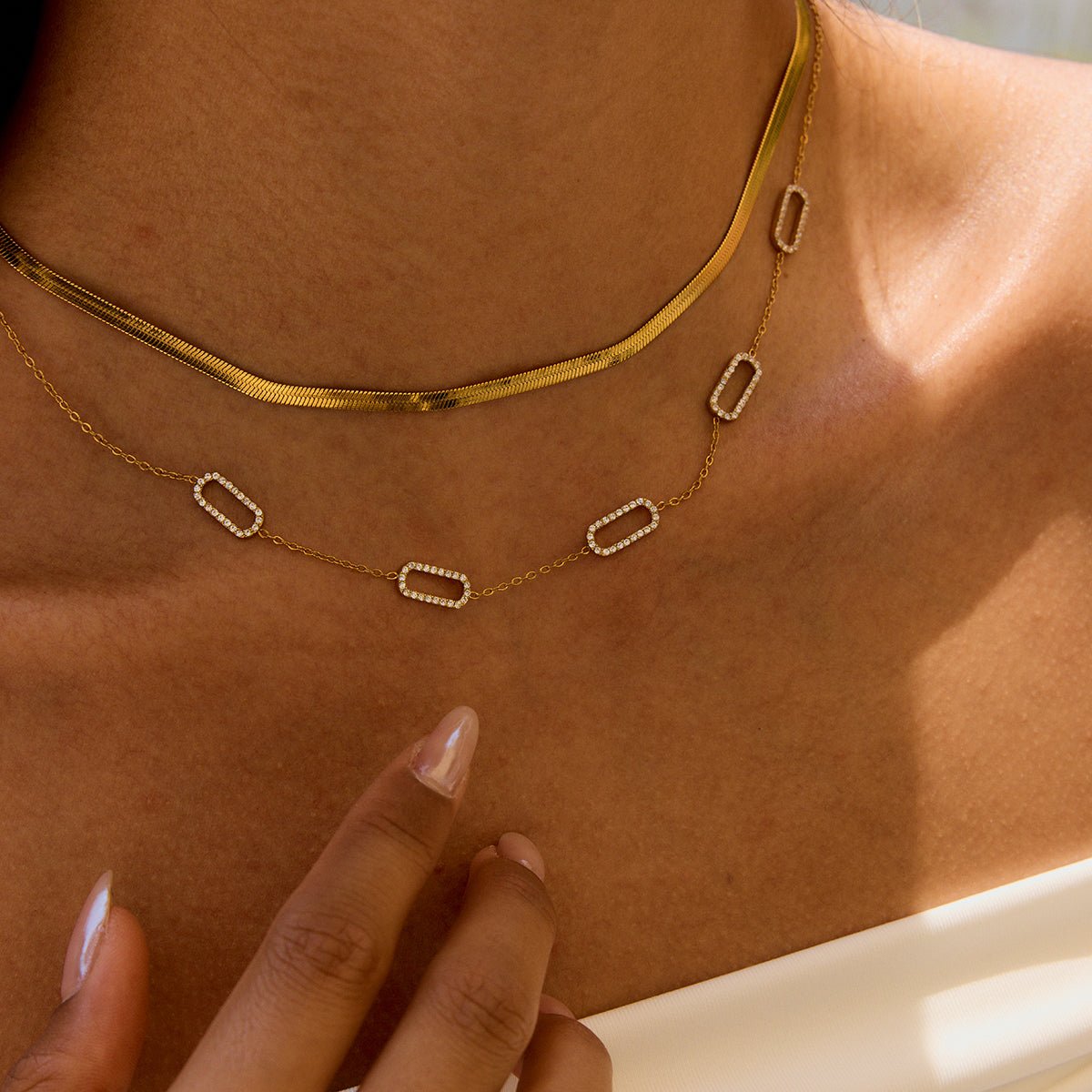 Gold necklace with diamond-like pendants on a person's neck