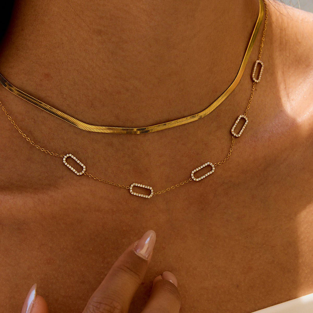 Gold sun-shaped necklace worn by a person with a blurred background