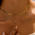 Gold sun-shaped necklace worn by a person with a blurred background