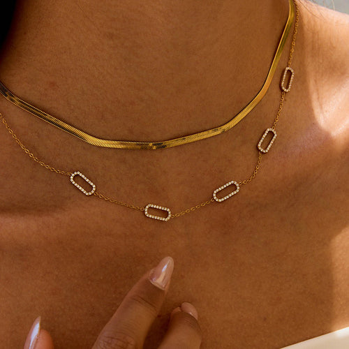 Gold sun-shaped necklace worn by a person with a blurred background