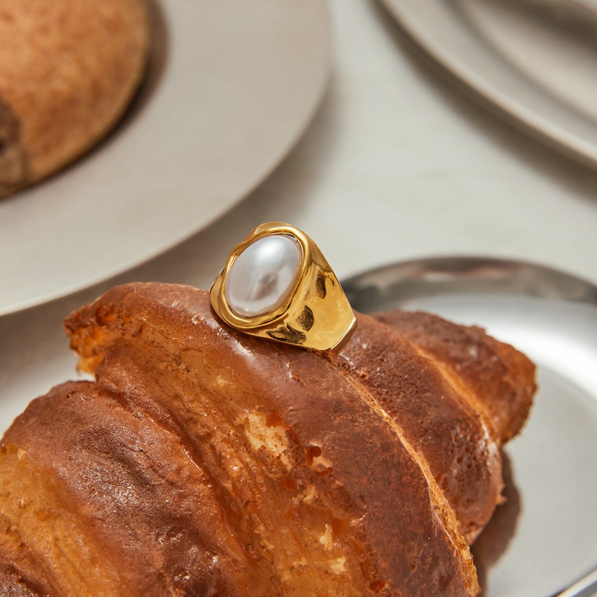 Gold ring with a pearl on a pastry High-shine gold ring featuring natural pearl

