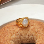 Gold ring with a pearl on a textured surface