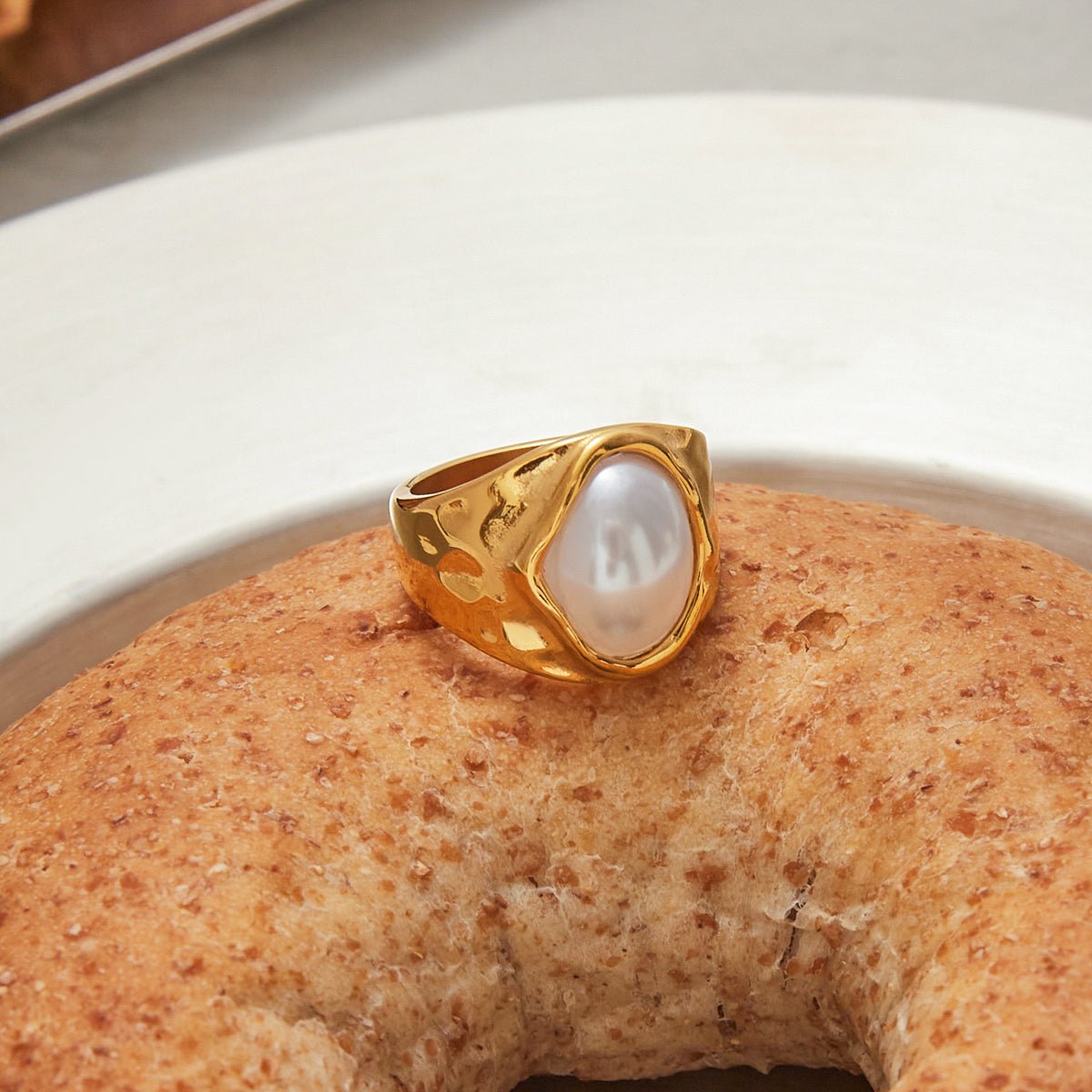 Gold ring with a pearl on a textured surface