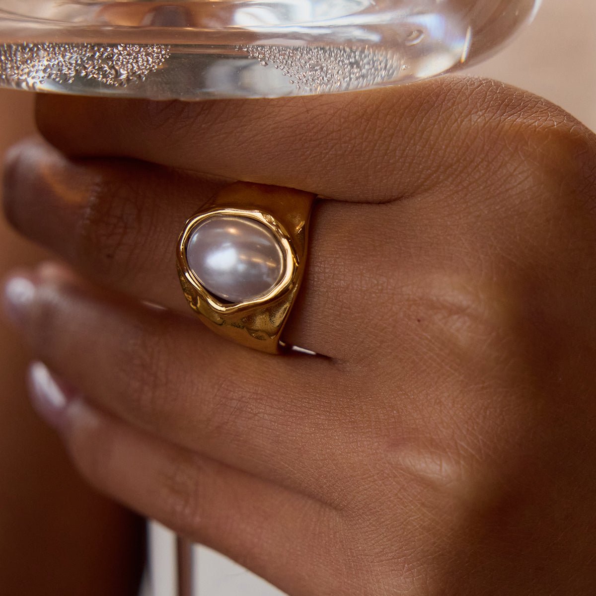Gold ring with a pearl on a hand