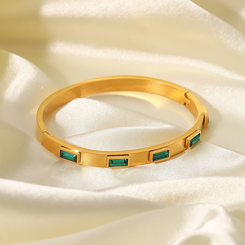 Sleek gold bangle with green accents
