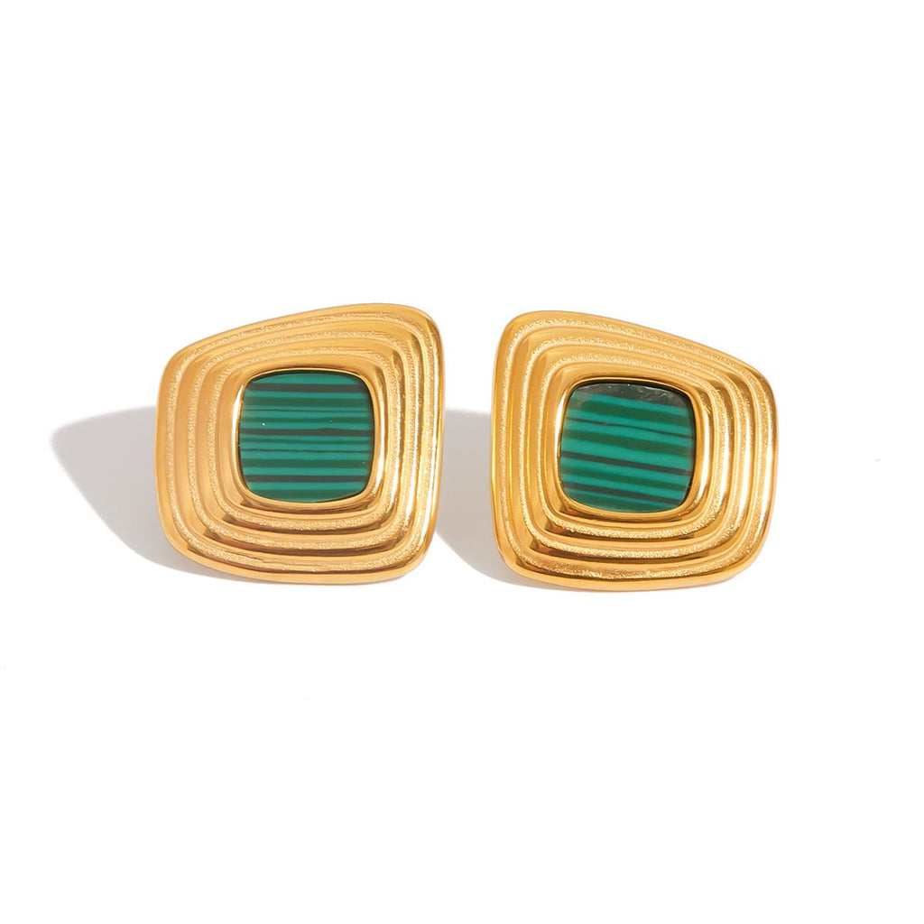 Gold earrings with green stones on a white background