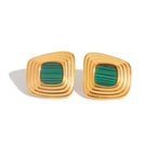 Gold earrings with green stones on a white background