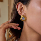 Gold earring worn by a person with a blurred background