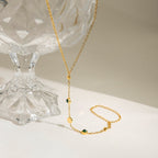 Gold necklace with green beads on a white surface with a glass pedestal