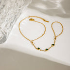 Gold hand chain bracelet with green gemstones

