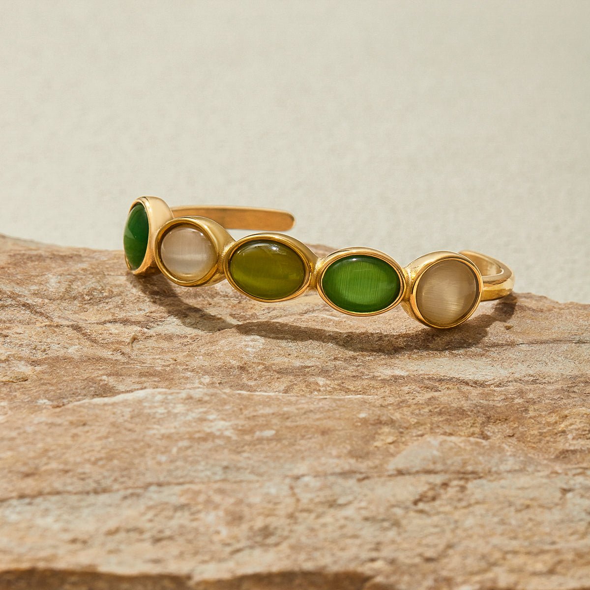 Artistic photo of gold cuff with white and green stones