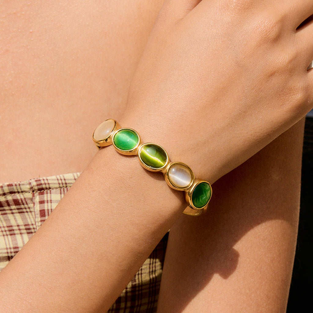 Gold cuff bracelet with green and white oval stones