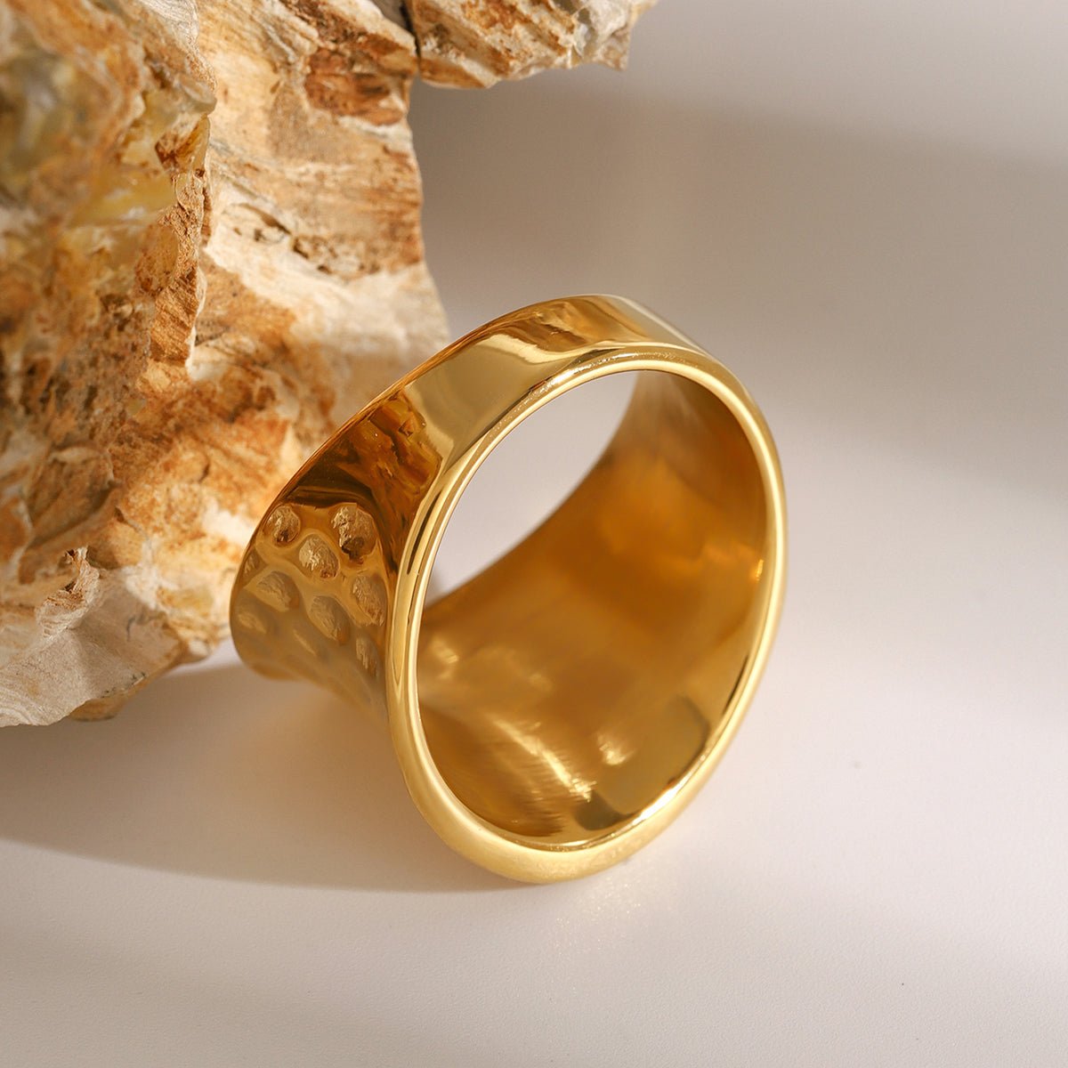 Gold ring with textured design on a neutral background