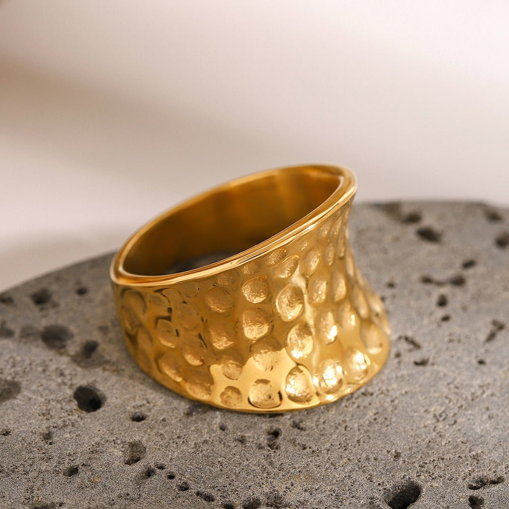 Gold ring with textured design on a gray surface