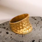 Gold ring with textured design on a gray surface