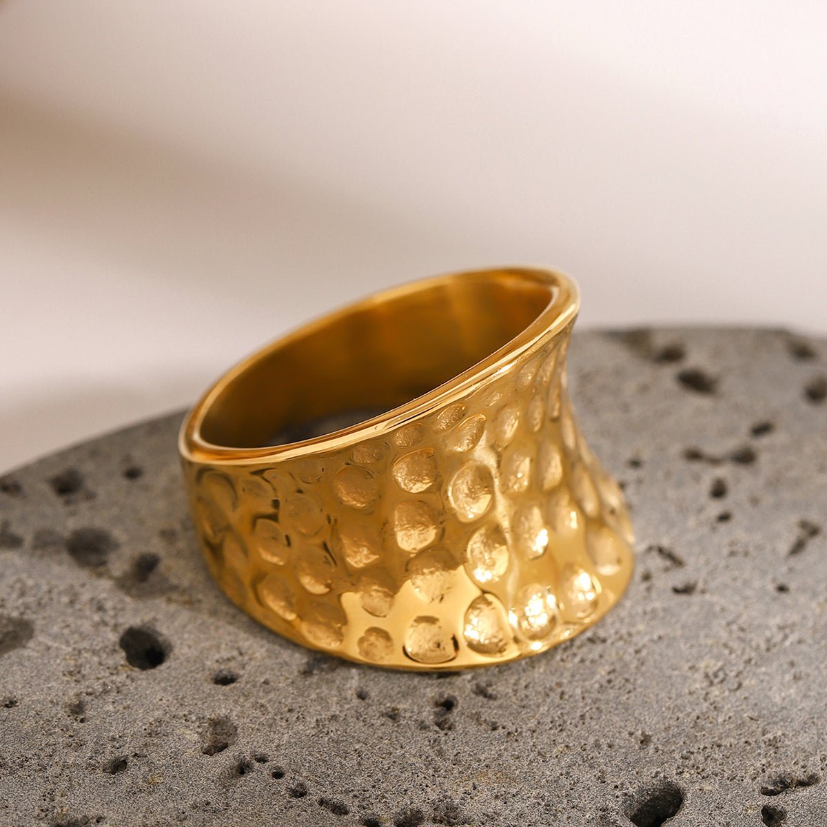 Gold ring with textured design on a gray surface
