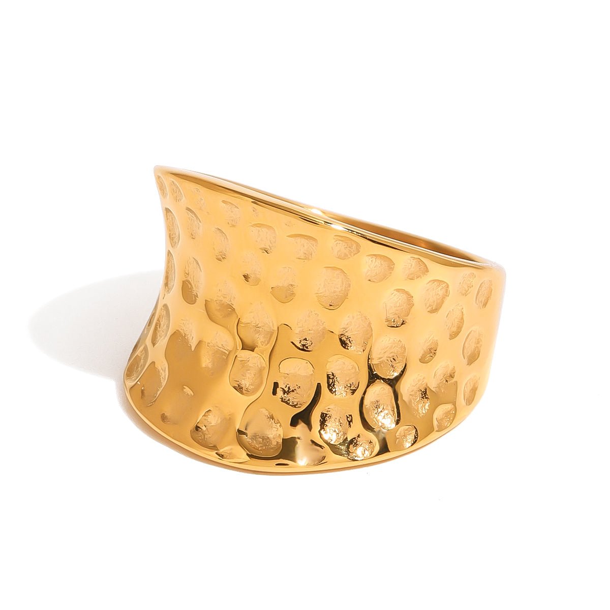 Gold cuff ring with textured surface on a white background