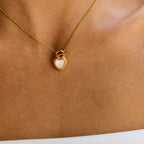 Gold necklace with a heart-shaped pendant on a person's neck