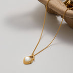 Gold necklace with a heart-shaped pendant on a light background