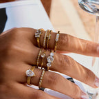 Hand wearing multiple gold and diamond rings with a blurred background