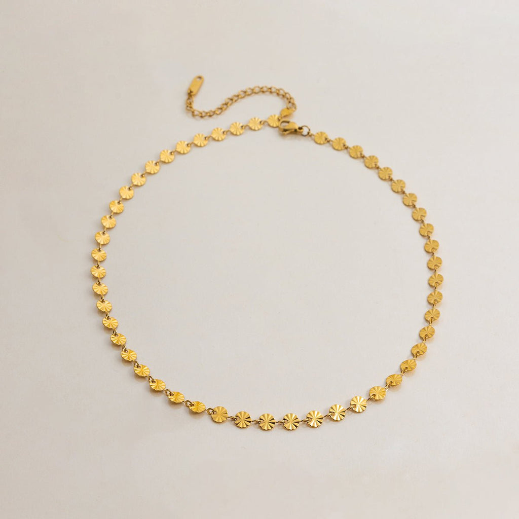 Gold necklace with star-shaped links on a light gray background