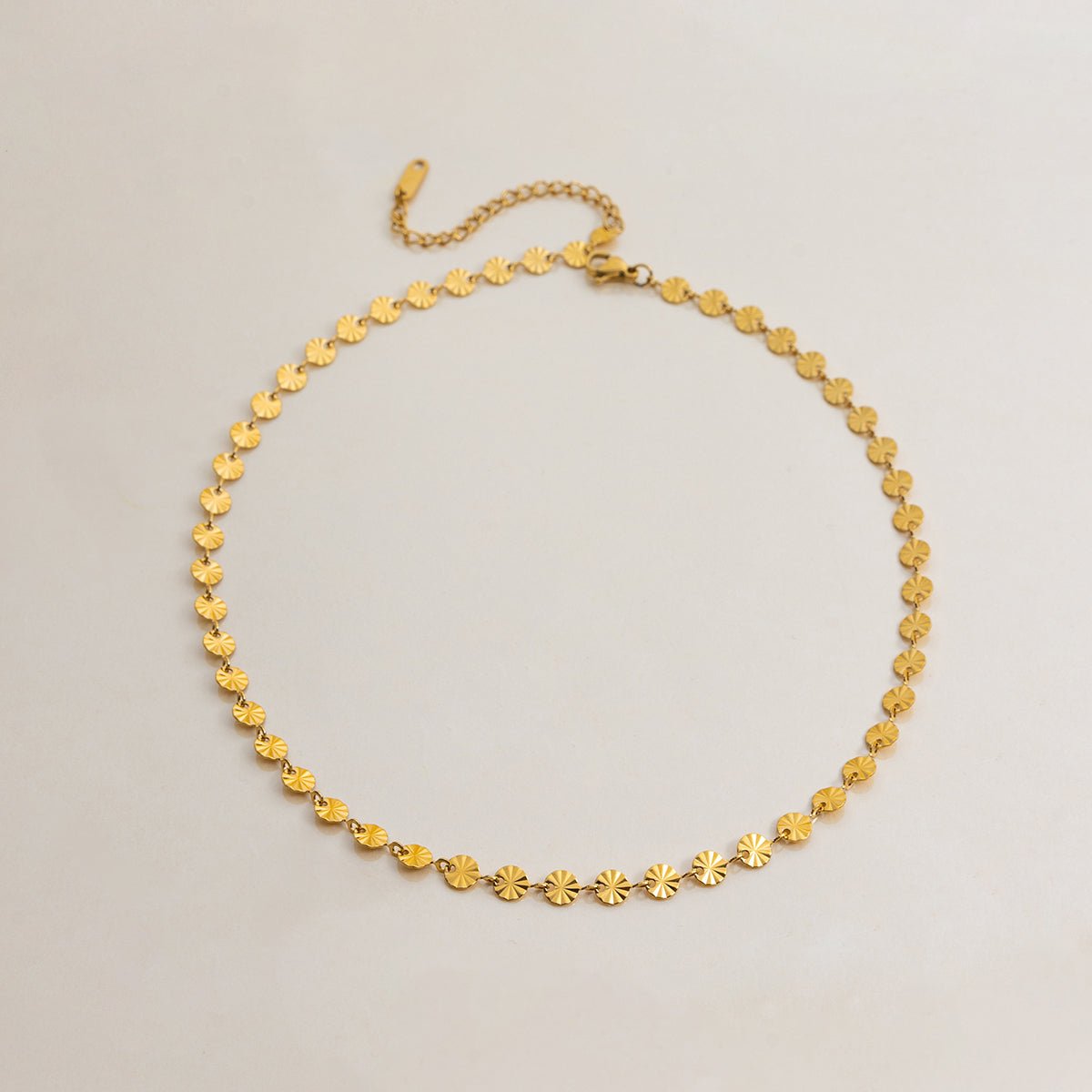 Gold necklace with star-shaped links on a light gray background