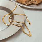 Gold necklace with a heart-shaped pendant on a white plate