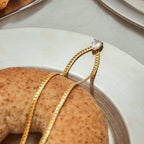 Gold chain with a diamond on a white plate with a donut