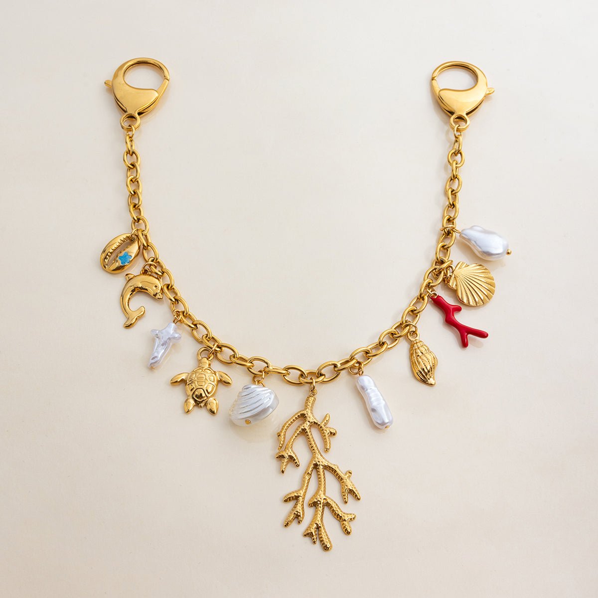 Gold charm bracelet with various sea-themed charms on a beige background