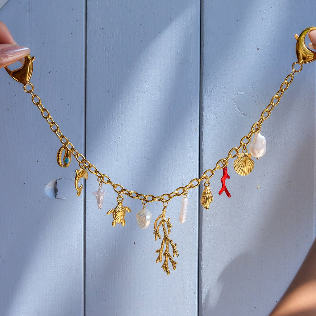 Gold necklace with various charms against a light blue wooden background