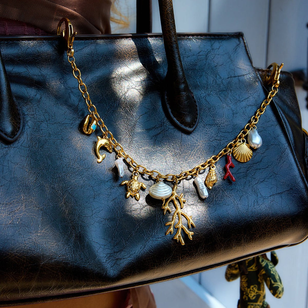 Black handbag with a gold charm necklace draped over it