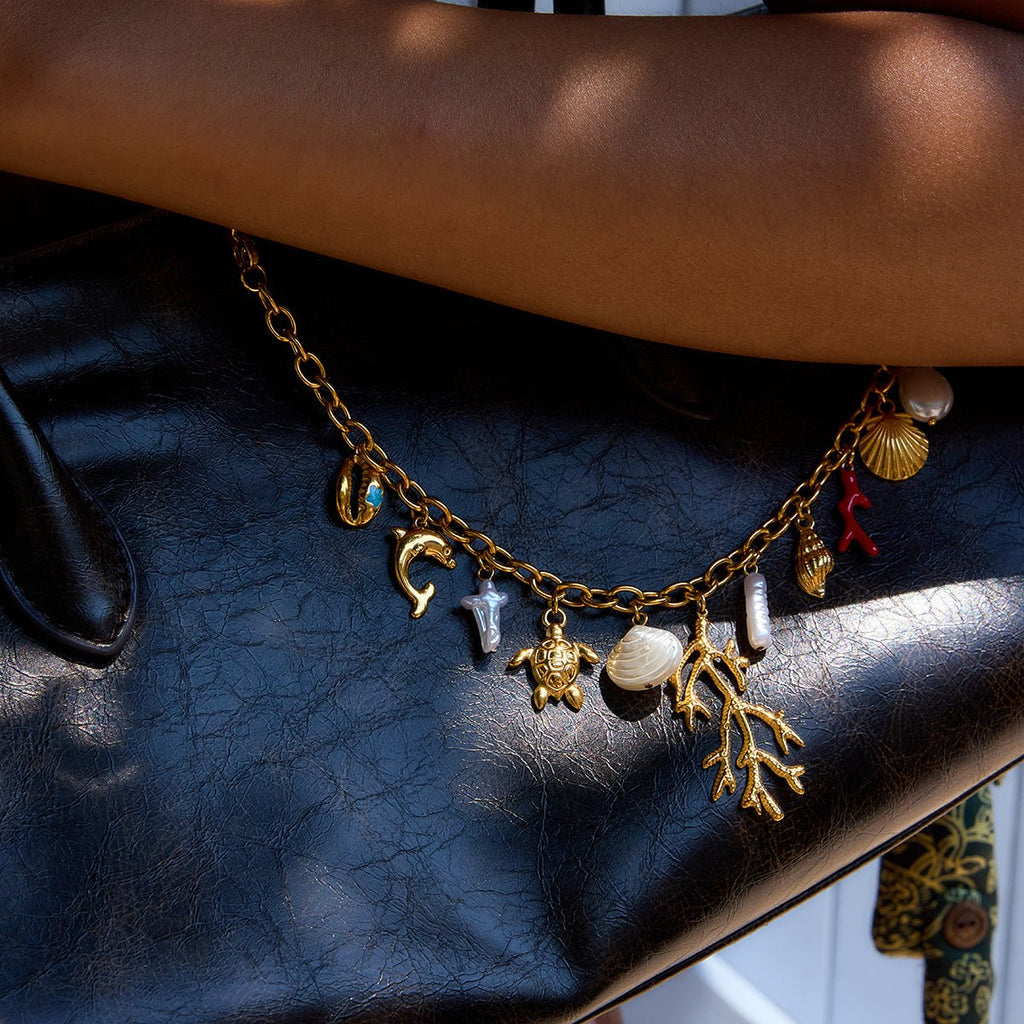 Gold charm bracelet with various charms on a black surface