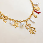 Gold charm bracelet with various sea-themed charms on a beige background