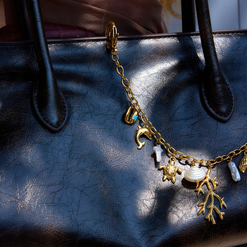 Gold charm bracelet with various charms on a textured black surface